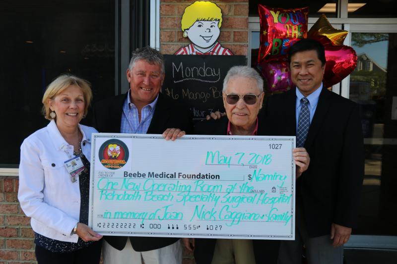 Outside Nicola Pizza on Rehoboth Avenue, with "Mama Nicola" Joan Caggiano looking over everyone from above are Nick Caggiano and his son Nick Jr. presenting a check to Judy Aliquo, Beebe Medical Foundation president; and Dr. Wilson C. Choy, orthopaedic surgeon and Beebe Healthcare Board of Directors member. Shown (l-r) are Aliquo, Nick Jr. and Nick Caggiano, and Choy. SUBMITTED PHOTO